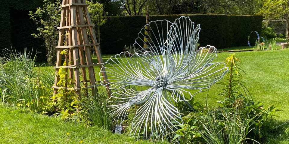 A medium Flora sculpture set in a border between lawns.