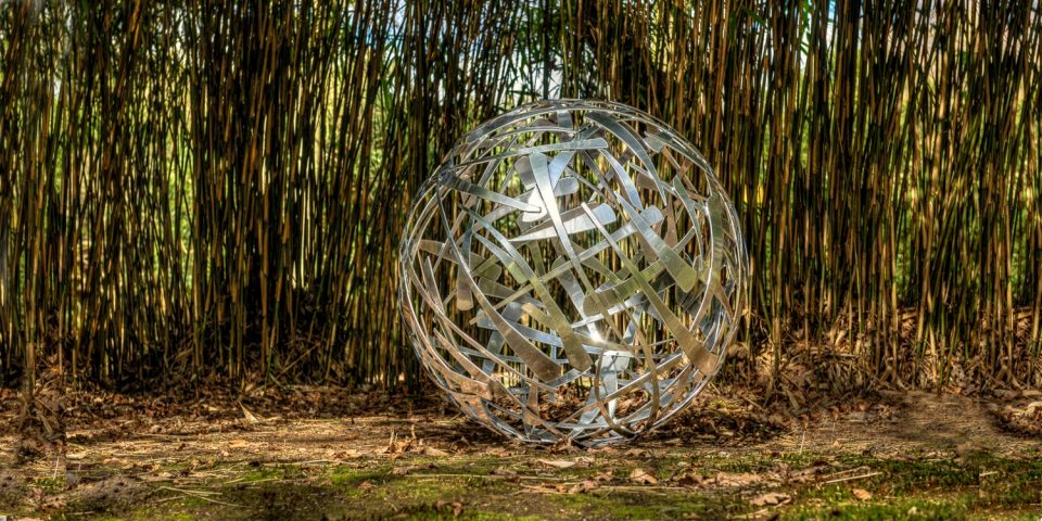 120cm diameter Calligraphy Ball, powder coat chrome colour finish in a clearing of bamboo stems.