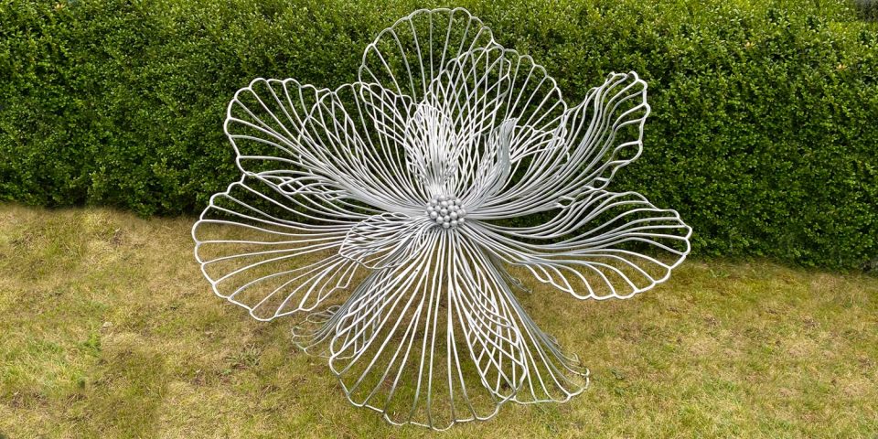 A medium Flora sculpture on a lawn against a box hedge.